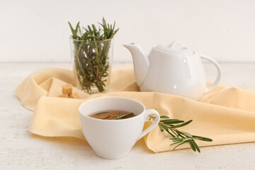 Teapot and cup of hot rosemary tea on white background