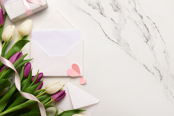 Envelopes with blank card and tulip flowers on white grunge background. International Women's Day celebration
