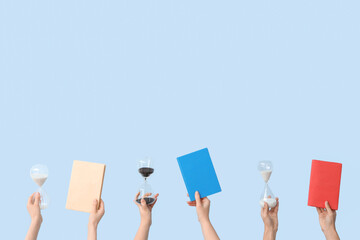 Female hands holding hourglasses and books on blue background