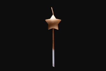 Magic wand isolated on black background. Magic wand or gold colored star shaped candle