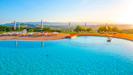 Fototapeta na wymiar Blue swimming pool and beautiful hilly panoramic landscape at sunset time