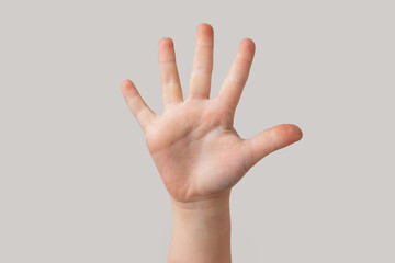 Child hand showing five fingers isolated on grey background, close-up