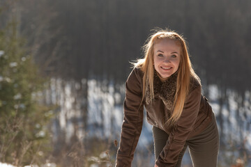 Portrait of smiling young woman with long hair outside in nature. Walk on sunny winter day.