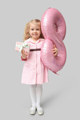 Cute little girl with pink air balloon in shape of figure 8 and gift box on grey background. International Women's Day