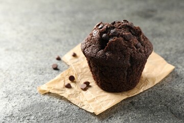 Delicious chocolate muffin on grey textured table, closeup. Space for text