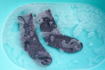 Dirty socks soaked in water, dissolving detergent in basin.