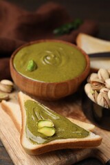 Toasts with tasty pistachio cream and nuts on wooden table, closeup