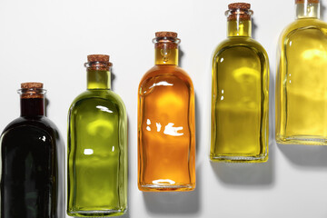Vegetable fats. Different cooking oils in glass bottles on white background, flat lay