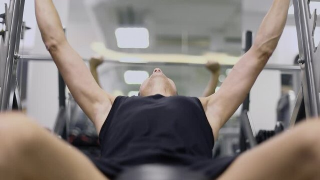 Man pulls bar with weight in gym of sport club. Slow motion
