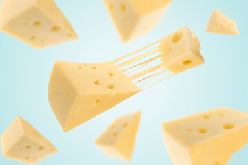 Pieces of cheese falling on light blue background