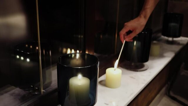 Kindling of candle on windowsill by long match. Slow motion