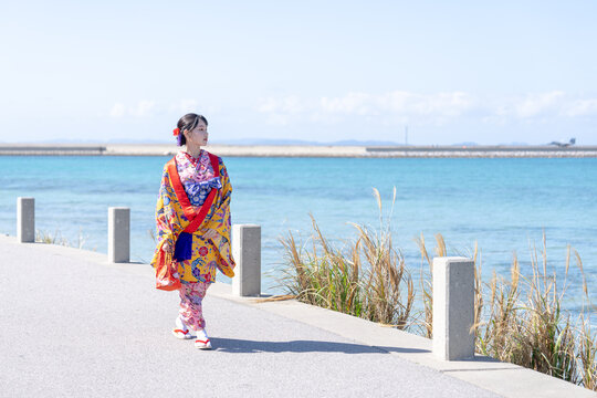 沖縄県豊見城市瀬長のウミカジテラスの海の見える場所で琉装を着た２０代の若い日本人女性 A young Japanese woman in her 20s in Ryukyu dress at a place with a view of the sea on Umikaji Terrace in Senaga, Tomigusuku City, Okinawa Prefecture