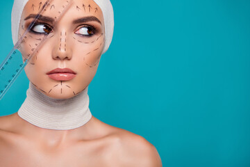 Photo of aesthetic medicine patient look over cyan empty space background measure face with ruler