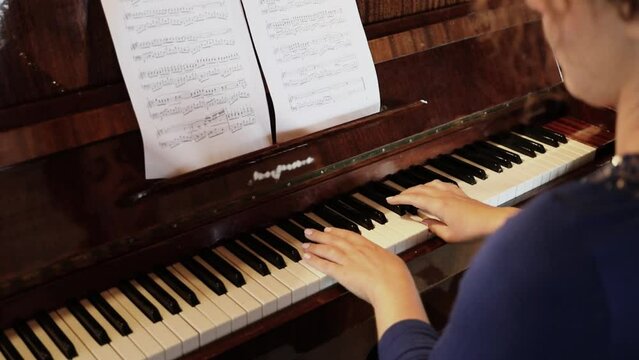 Woman Plays From Music On Piano, Close View From Behind. Slow Motion