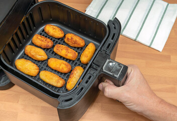 HAND COOKING HOMEMADE CROQUETTES RECIPE IN AIR FRYER AT THE KITCHEN. TOP VIEW.