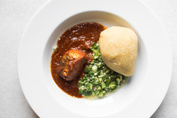 Nigerian okro and stew with eba in a white plate, top view of okro soup and eba