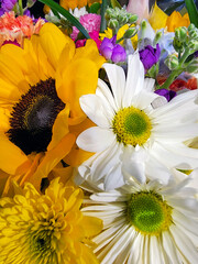 A spring bouquet of mixed flowers including sunflowers, white daisies, and yellow  chrysanthemums.