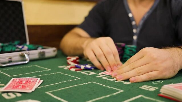 Man looks and hides his cards during poker game on table with chips