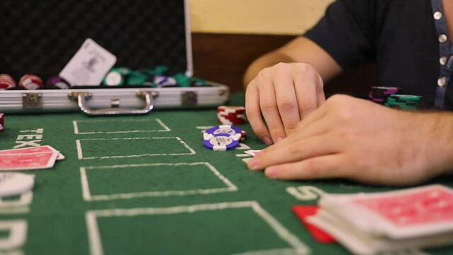 Man holds hands on cards during poker game on table with chips