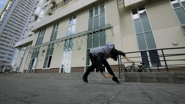 Man performs break-dance and makes somersault on street. Slow motion