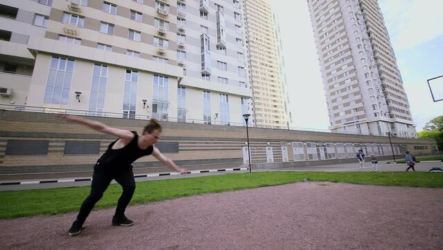 Young man makes acrobatic performance on sports playground. Slow motion