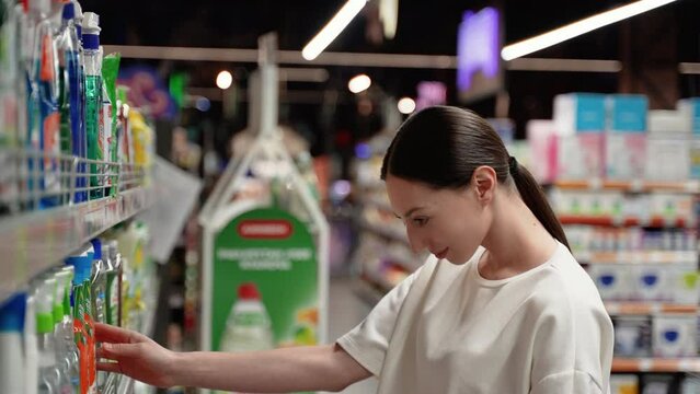 A woman chooses a glass washer in a supermarket