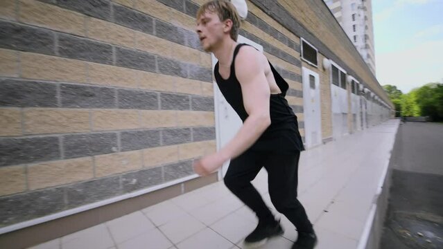 Young man traceur runs and makes flip during jump on wall. Slow motion