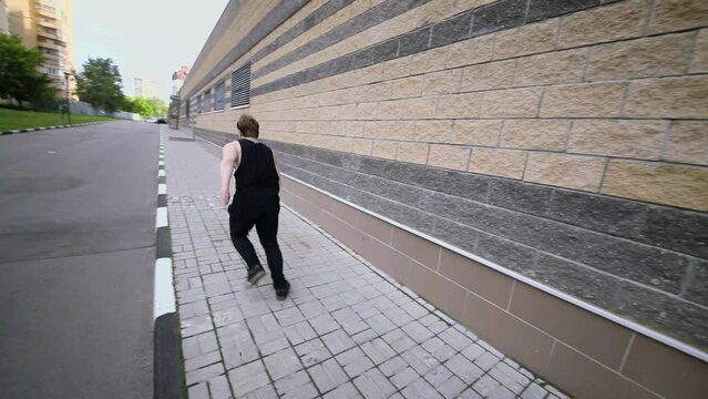 Young man does somersault during jump on wall. Slow motion