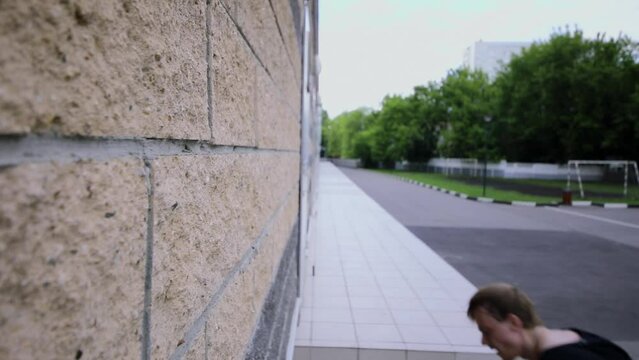Young man jumps on wall and makes flip. Slow motion