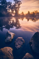 Rocks at calm lake shore during sunrise. High quality photo - 730451600