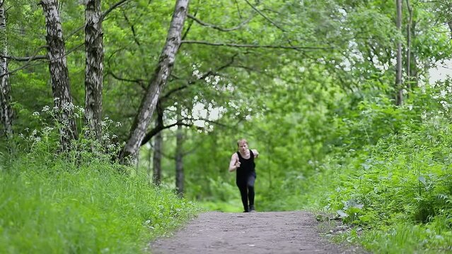 Man runs and does side flip on footpath during parkour training in park. Slow motion