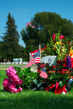 A tombstone covered with flowers and American flags honoring a soldier who made the ultimate sacrifice.