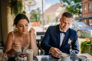 Valmiera, Latvia - July 7, 2023 - A bride and groom are enjoying desserts and coffee at a street...