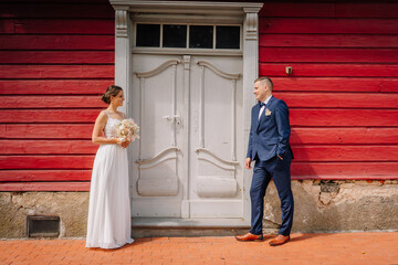 Valmiera, Latvia - July 7, 2023 - Bride and groom standing apart, facing each other smiling, in...