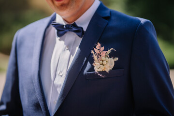 Valmiera, Latvia - July 7, 2023 - Close-up of a groom's blue suit with a white shirt, navy bow tie,...