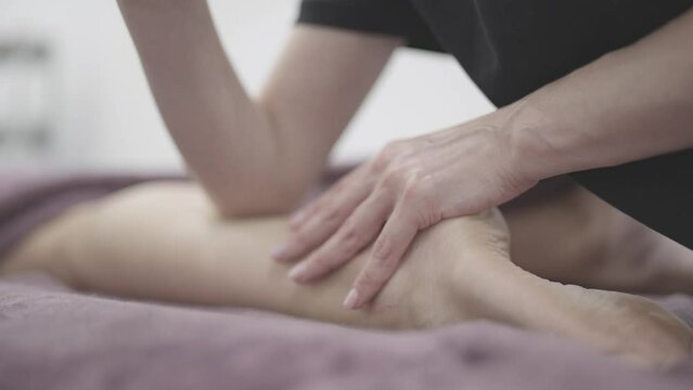 Masseur Providing a Deep Tissue Leg Massage at Spa