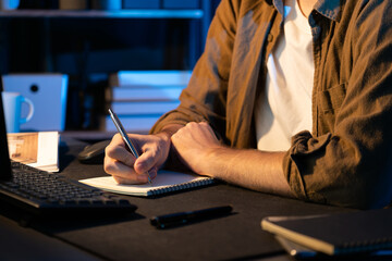 Cropped image of young businessman writing design thinking on paper for new project at neon light...
