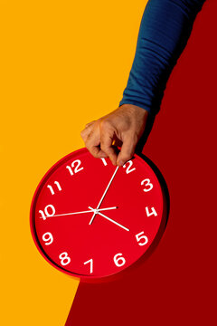 Hand adjusting a red clock on a colorful background