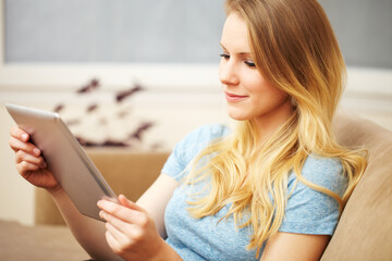 Young Woman Reading a Digital Tablet on Sofa