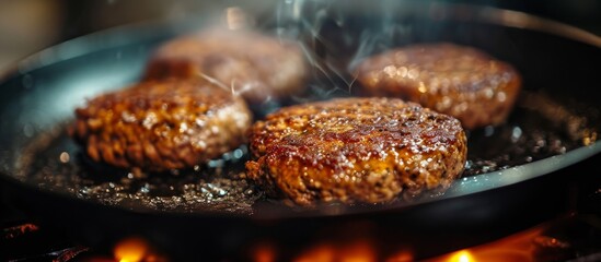 Close-up of homemade hamburger cutlets grilling in a pan.
