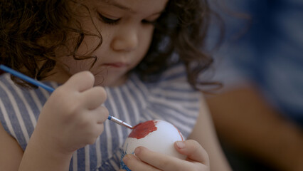 Father and daughter paint eggs at Easter.