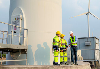 A team of wind turbine expert engineers discusses clean energy production in wind farms. Clean...