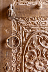 Metal pull and knocker on a carved wooden door in the Al-Balad historical district.