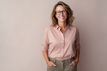 Smiling mature woman wearing glasses standing with hands in pockets and looking at camera