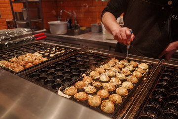 Selective focus at Takoyaki, ball-shaped Japanese snack made of a wheat flour-based batter and cooked in a special molded pan.