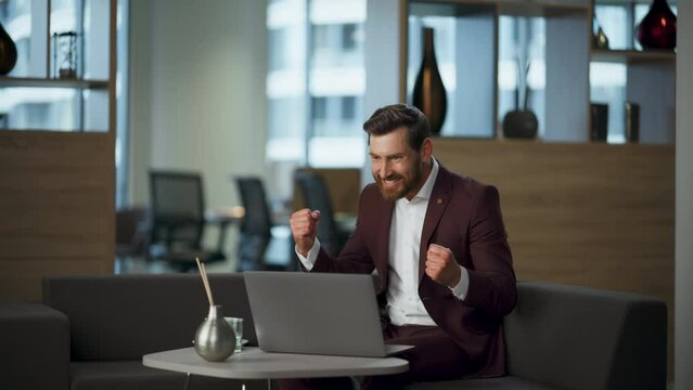 Surprised winner looking computer screen working office. Rich manager rejoicing
