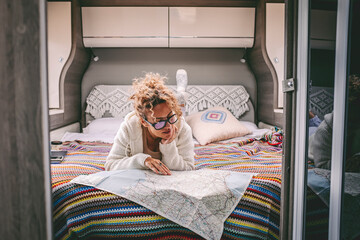 One woman planning next travel trip destination laying in bed inside a mpodern camper van...
