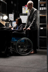 Obraz premium Paralyzed asian businesswoman executive sitting in wheelchair at office desk, inspecting quarterly results analysis data on laptop. Woman with paraplegia in accountancy workplace