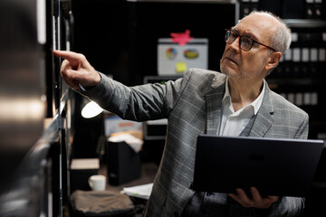 Senior private detective in criminal cases archive room looking for criminal case file details on...