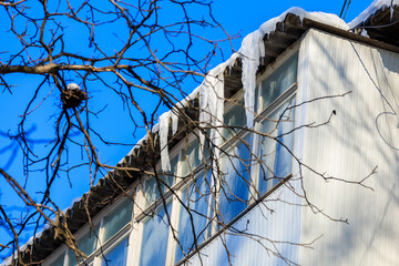 Large icicles on the roof pose a danger to passersby. Background with selective focus and copy space